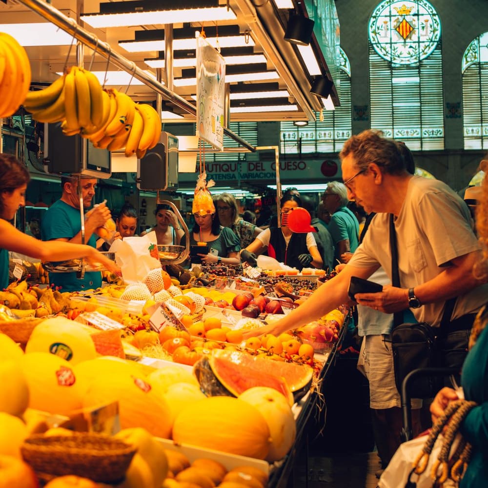 Ambiente del mercado con vecinos comprando por el pasillo central